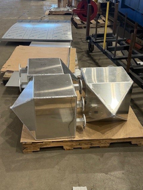 Production CAST units in the shop — real hardware, pointed hoppers; shipping scale shown on pallet